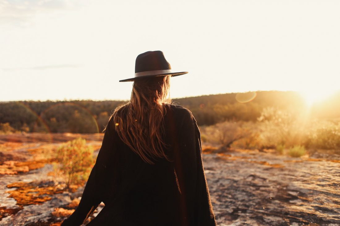 unrecognizable woman in hat standing on stony hill