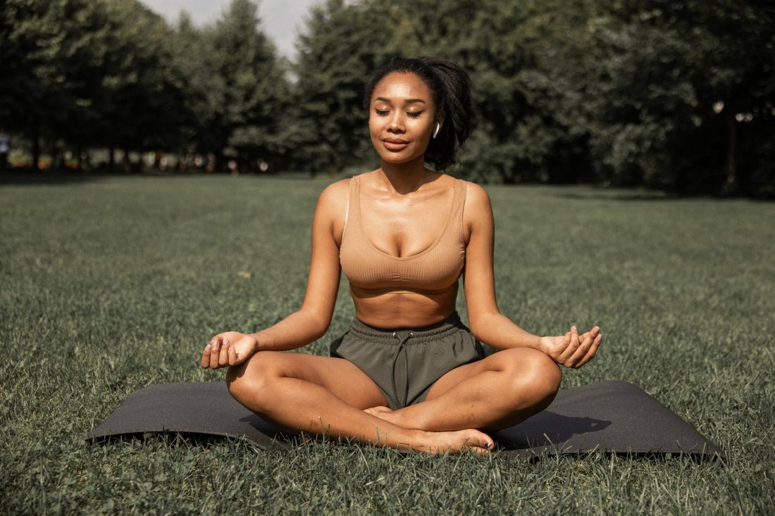 fit ethnic woman practicing yoga in park
