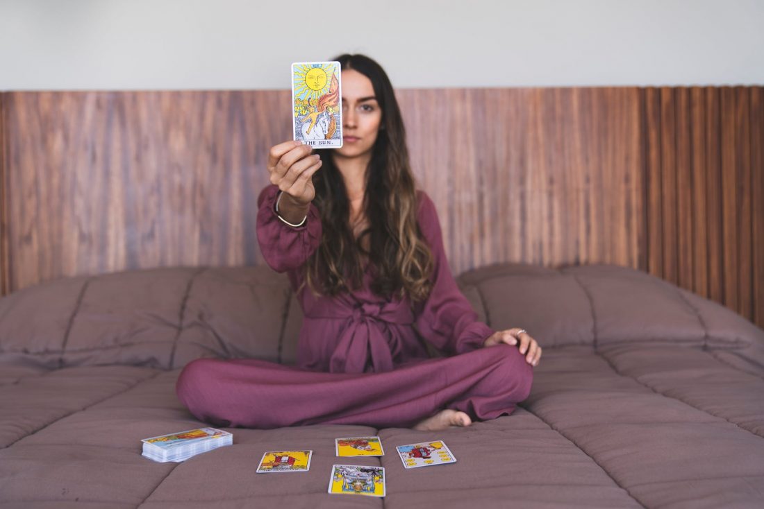 curly haired female holding a tarot card