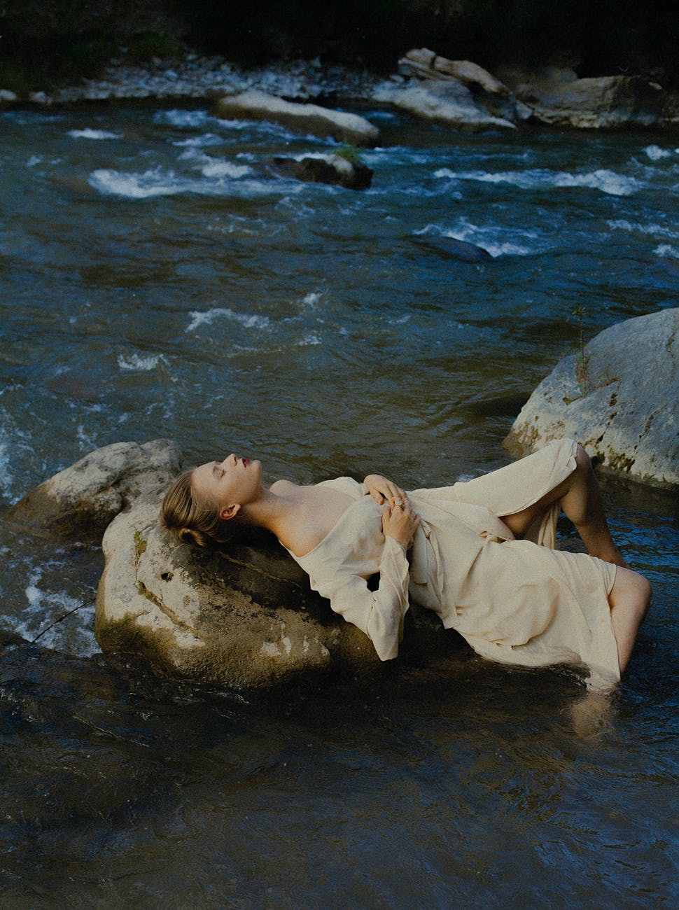 woman lying on rocks in water