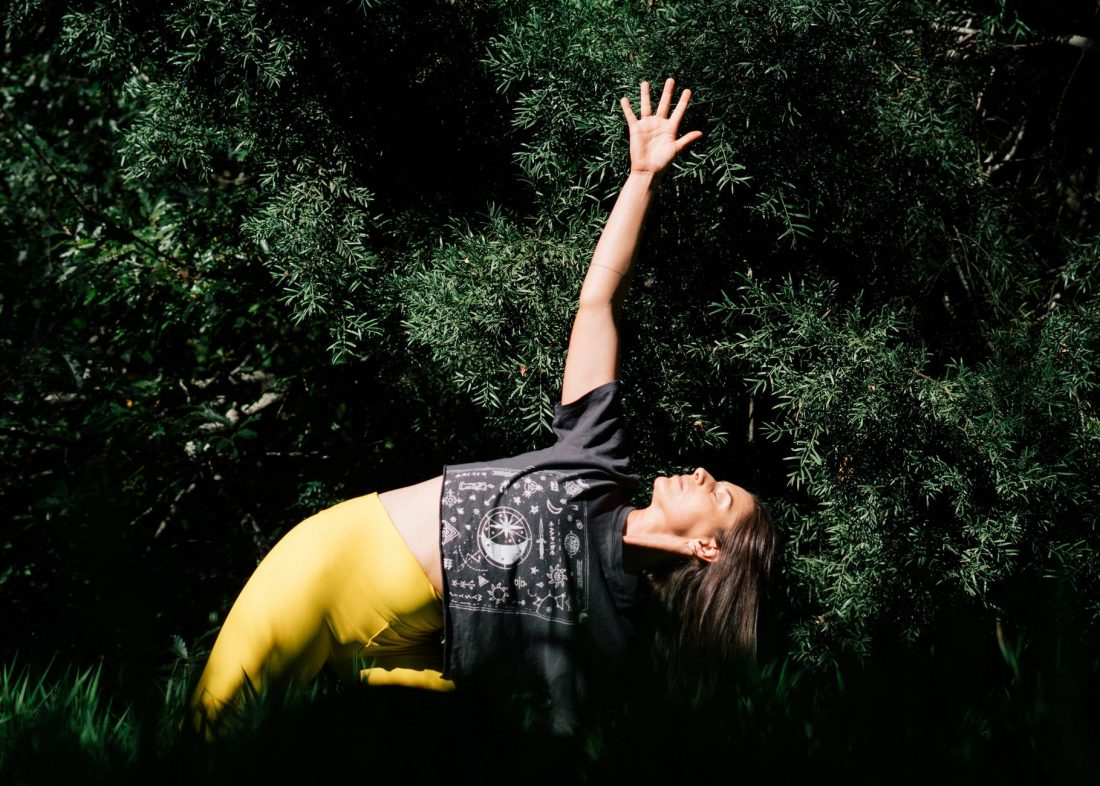 photo of woman doing yoga near dark green leaves