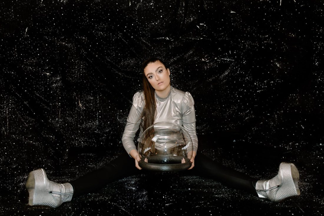 woman in beige long sleeve shirt and blue denim jeans sitting on black rock
